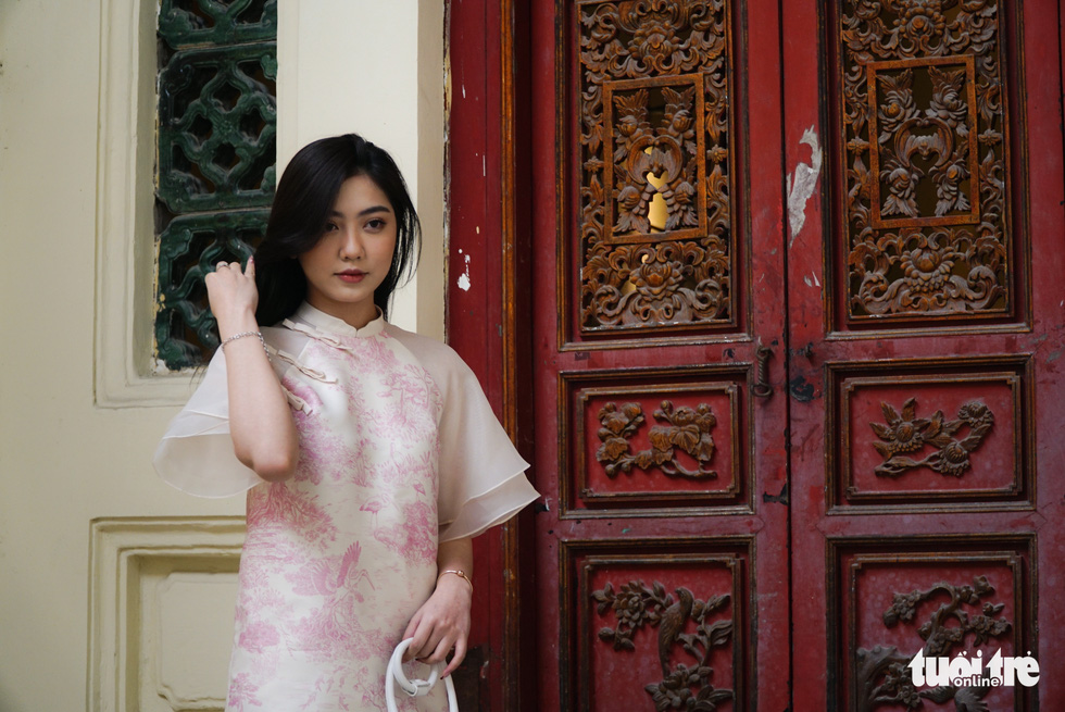 A young Hanoian lady poses for pictures in front of the door leading to the Mother Goddess Worship hall in the Cantonese Assembly Hall. Photo: Nguyen Hien / Tuoi Tre