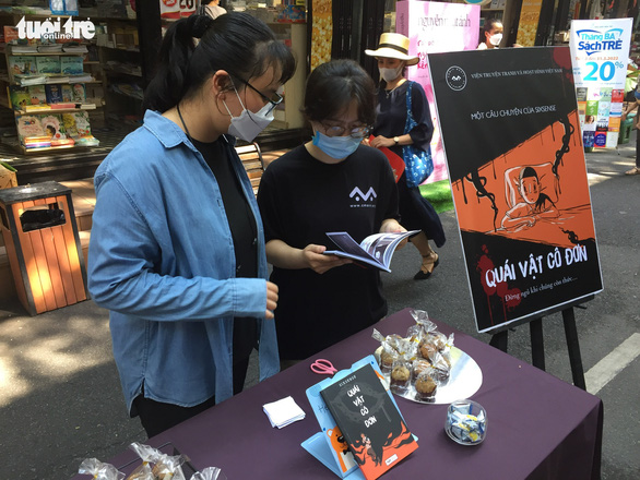 Two young women take a look at the comic books at the Hunted Project exhibition on Nguyen Van Binh Street, District 1, Ho Chi Minh City, Vietnam, on March 13, 2022. Photo: Mai Thuy / Tuoi Tre