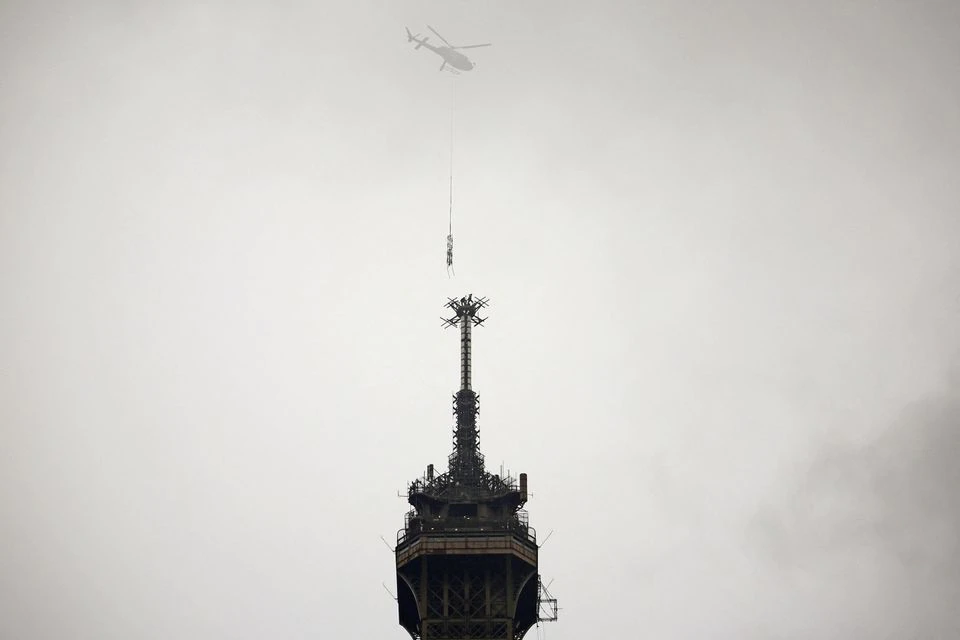 Workers inside a helicopter install a new telecom transmission TDF (TeleDiffusion de France) antenna on the top of the Eiffel Tower in Paris, France, March 15, 2022. Photo: Reuters