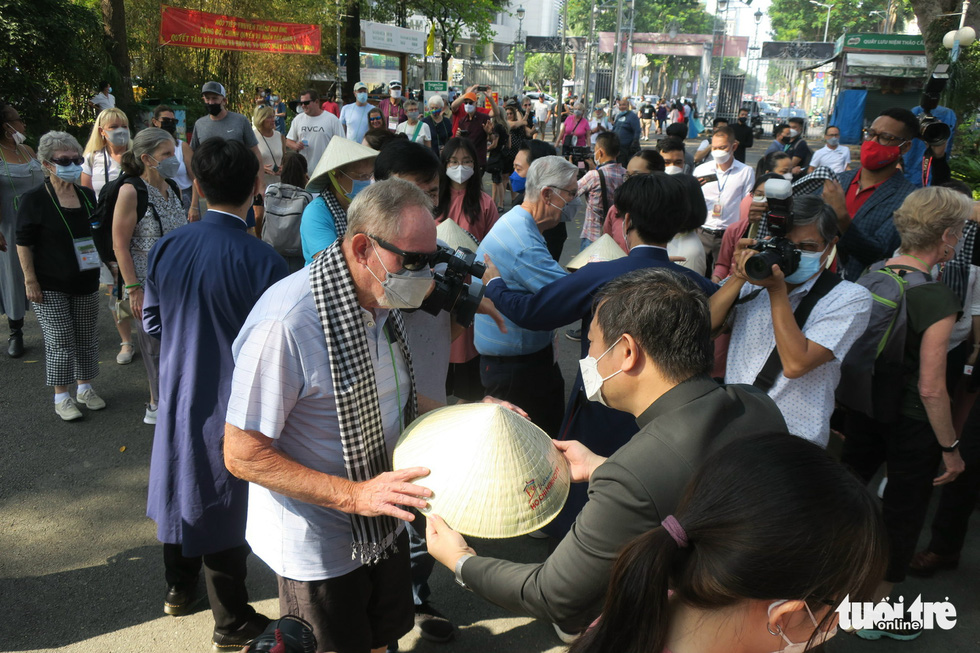 Deputy chairman of the Ho Chi Minh City administration Duong Anh Duc presents a palm-leaf conical hat to a member of the American tourist group. Photo: T.T.D. / Tuoi Tre