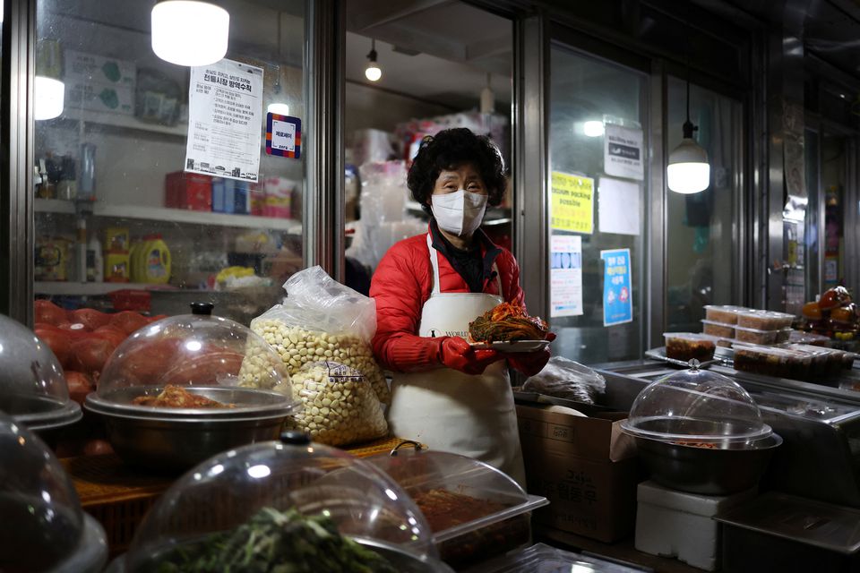 Choi Sun-hwa poses for a photograph with traditional Korean side dish kimchi at her side dish store at a traditional market in Seoul, South Korea, April 7, 2022. Photo: Reuters