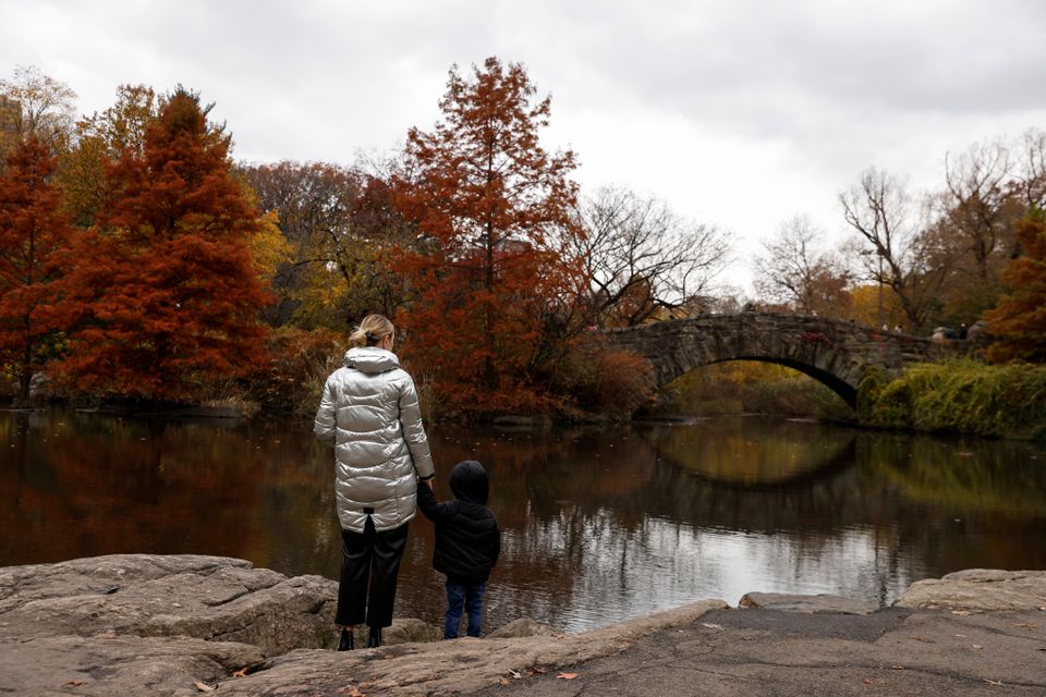 A woman holds the hand of a child by a pond at Central Park in New York City, U.S., November 22, 2021. Photo: Reuters