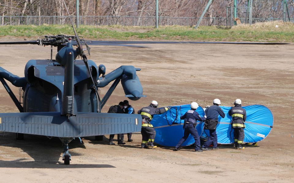 Firefighters and police officers transport rescued people from the missing tour boat 'Kazu 1' from Japanese Self-Defence Force's helicopters in Shari, Hokkaido Prefecture, Japan in this photo taken by Kyodo on April 24, 2022. Photo: Kyodo/via REUTERS
