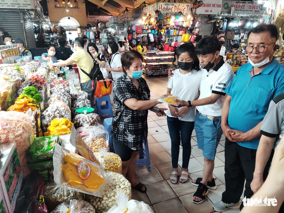 Stalls which provide food, fruits and confectionery at Ben Thanh Market get crowded again. This photo shows a group of South Korean tourists inspecting dried fruit and products at the market on April 24, 2022. Photo: N.Tri / Tuoi Tre