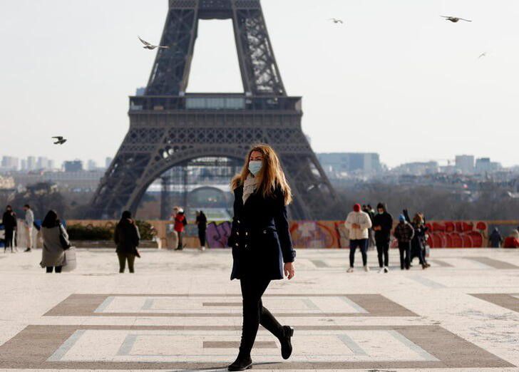 A woman, wearing protective face masks, walks in front of the Eiffel tower at the Trocadero in Paris in France, February 11, 2021. Photo: Reuters