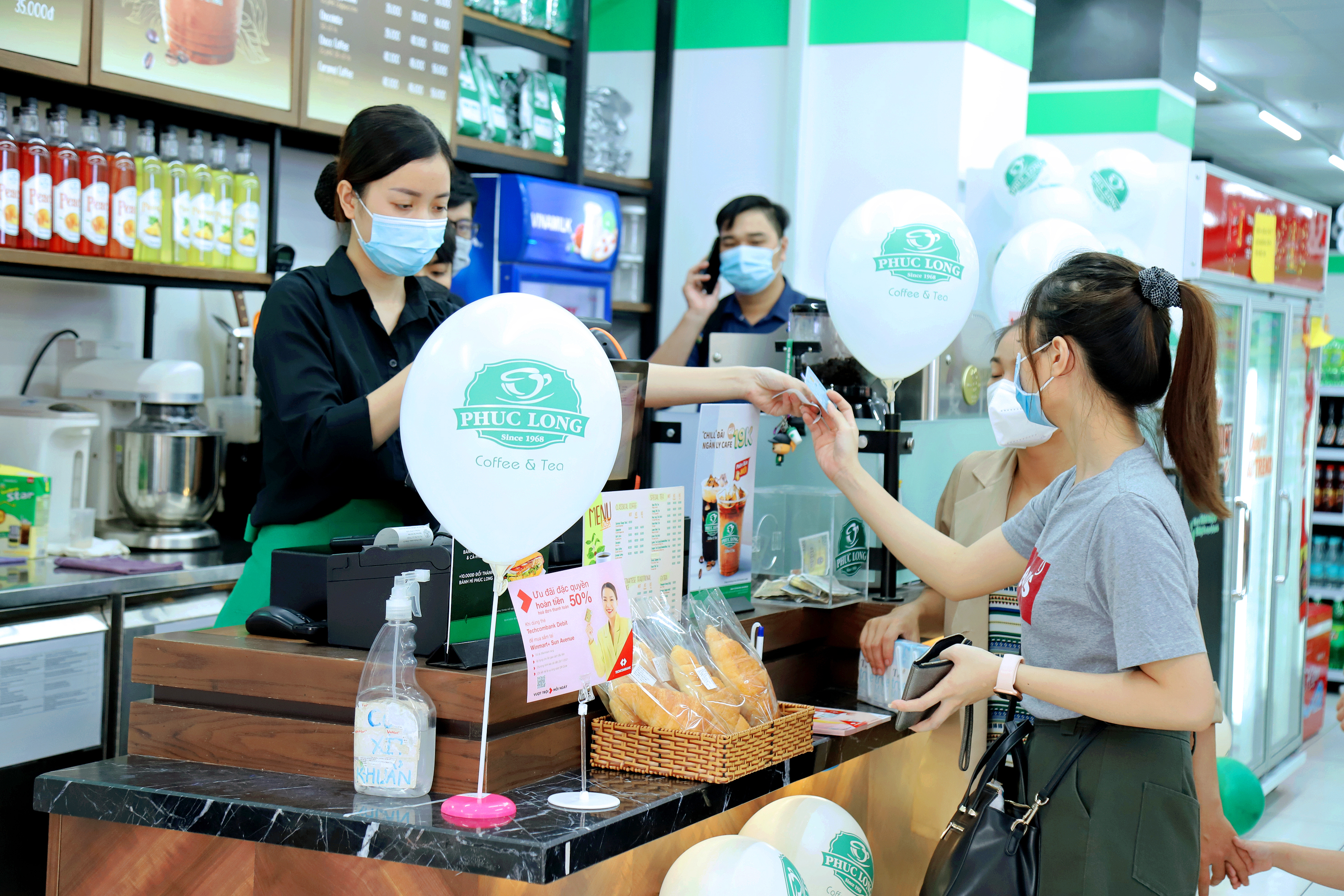 A customer buys beverage at a Phuc Long kiosk inside a WinMart+.