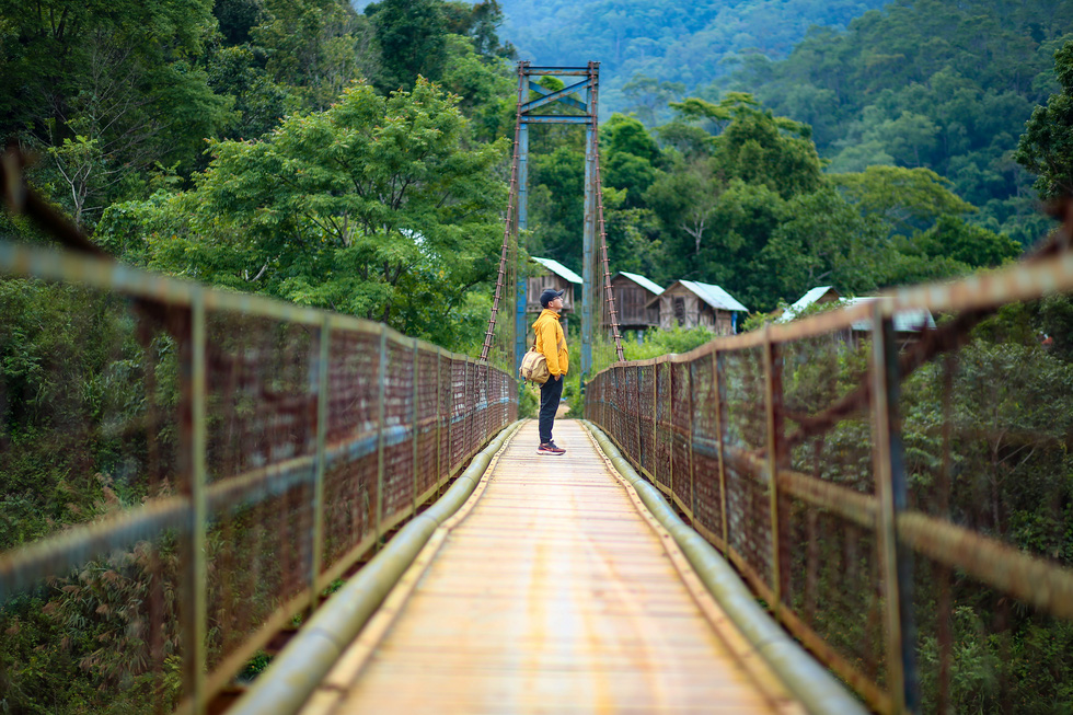 A visitor poses for a photo at the suspension bridge in Mang Den Town, Kon Plong District, Kon Tum Province, Vietnam. Photo: Do Do / Tuoi Tre