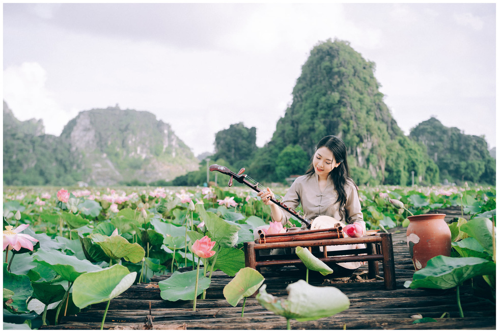 A young woman poses for a photo at a lotus pond at Tam Coc - Bich Dong landscape complex in Ninh Binh Province, Vietnam. Photo: Tiem anh 23.4 / Handout via Tuoi Tre