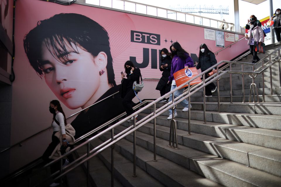 Fans of K-pop boy band BTS walk past an advertisement promoting their concert at Seoul Olympic stadium in Seoul, South Korea, March 10, 2022. Photo: Reuters