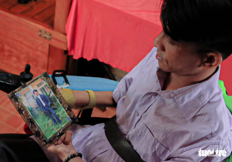 Nguyen Ngoc Lam is holding a photo of him taken in Binh Phuoc Pedagogic College in 2004.