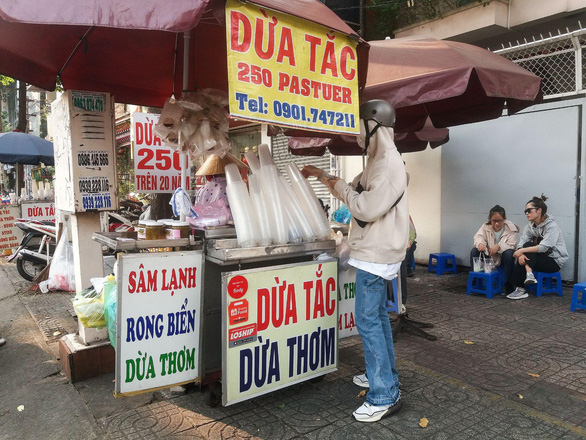 A customer buys coconut water at the 'dua tac' stall in front of 250 Pasteur Street in District 3, Ho Chi Minh City. Photo: Minh Duc / Tuoi Tre