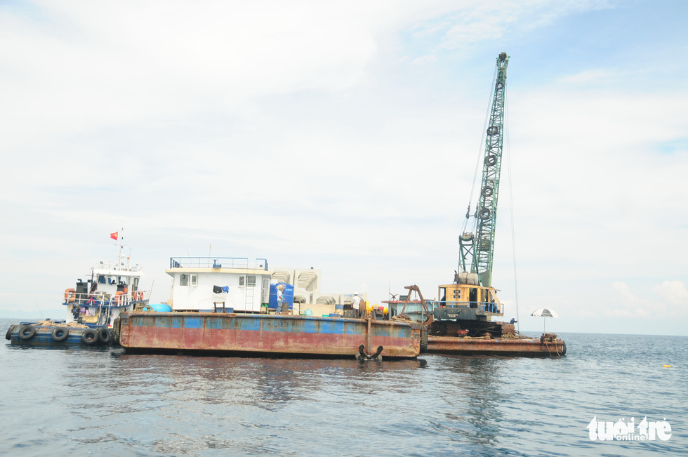 A picture showing a barge carrying a crane truck and concrete blocks to the working site.