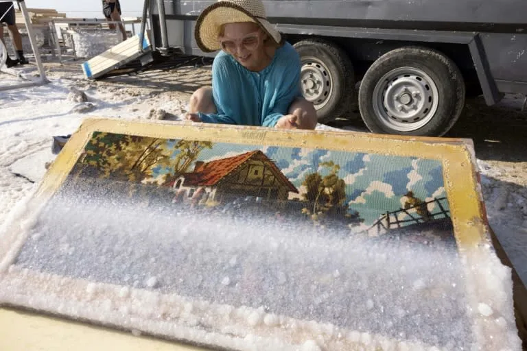 Multidisciplinary Israeli artist Sigalit Landau inspects one of her artworks, after being submerged in the salty Dead Sea water at the Ein Bokek resort, on August 2, 2022. Photo: AFP