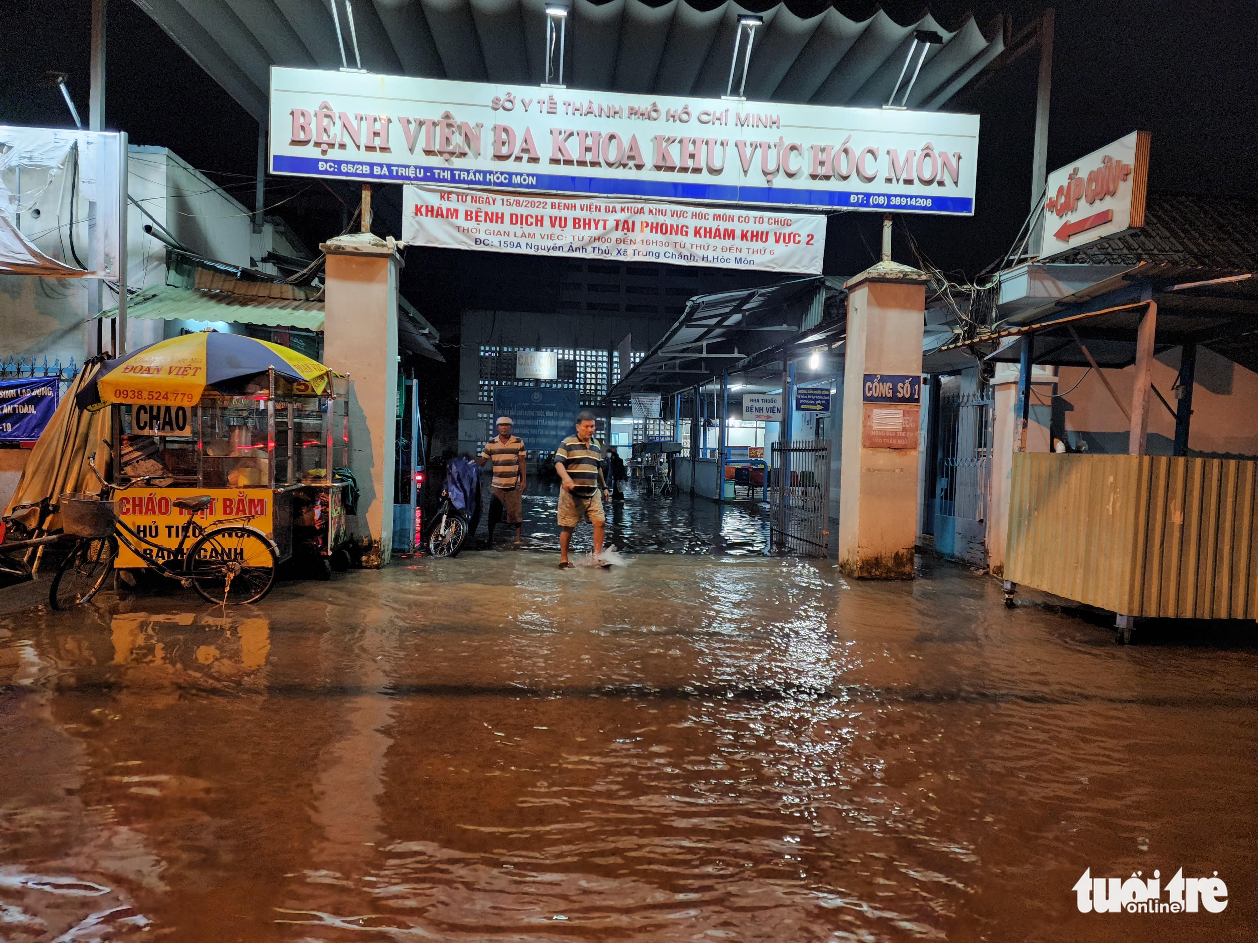 Men wade through rainwater at Hoc Mon General Hospital in Hoc Mon District, Ho Chi Minh City, August 15, 2022. Photo: Ngoc Khai / Tuoi Tre