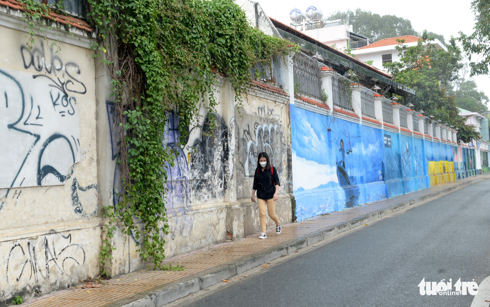 Distasteful graffiti and a beautiful picture are both seen on a wall along Nguyen Huu Canh Street in District 1. Photo: T.T.D. / Tuoi Tre