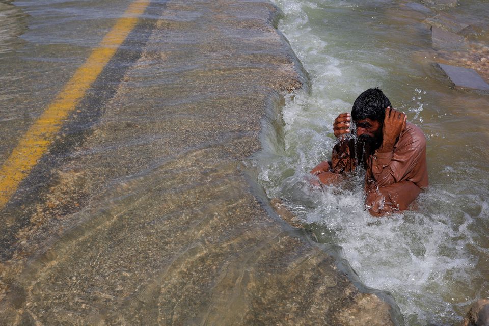 A displaced man cools off to avoid heat on flooded highway, following rains and floods during the monsoon season in Sehwan, Pakistan, September 16, 2022. Photo: Reuters