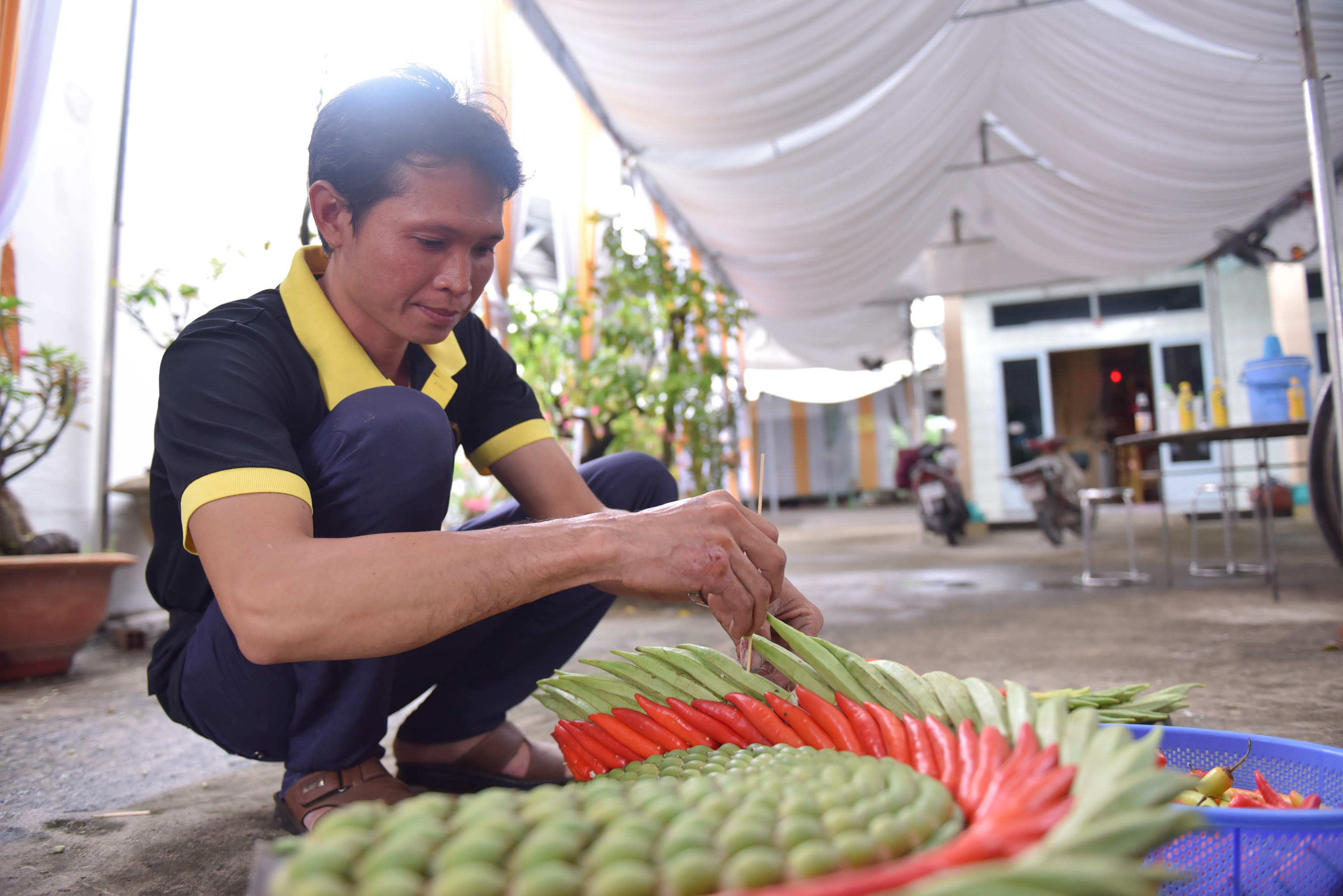 Pham Ut Tret, a member of Hieu’s team, is positioning okras and chillies on the dragon. Photo: Ngoc Phuong / Tuoi Tre News.