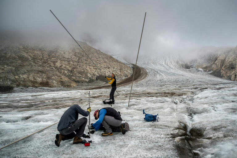 This picture taken on September 2, 2022 above Ulrichen shows glaciologist and head of 'Glacier Monitoring in Switzerland' (GLAMOS) network Matthias Huss (with yellow shirt) during a visit with his team on the Gries glacier to takes readings of measuring equipment. Photo: AFP
