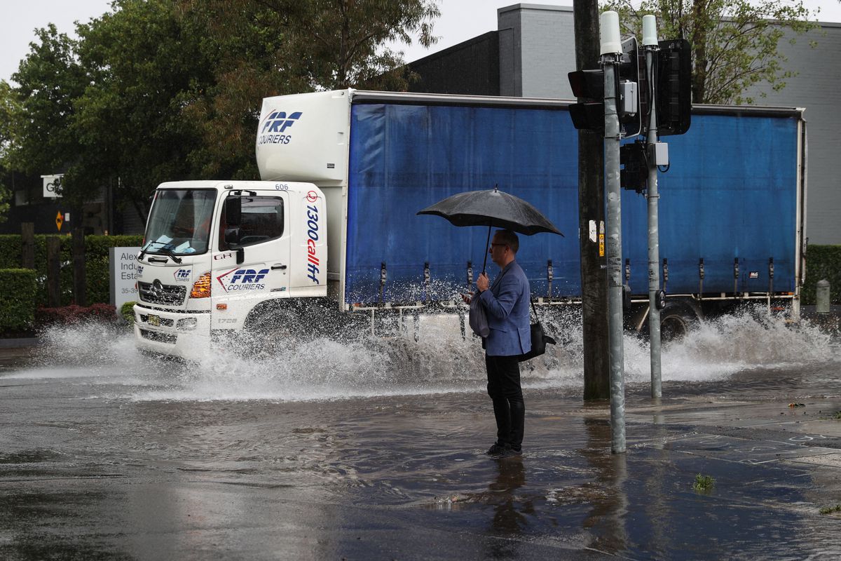 A pedestrian stands on the corner of a flooded street as heavy rains affect Sydney, Australia, October 6, 2022. Photo: Reuters