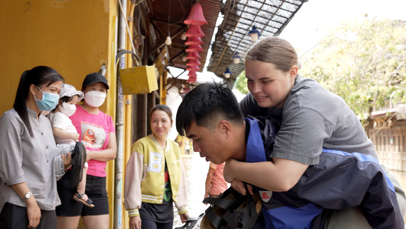 A foreigner is seen carried by a man on his back from a small boat to a destination in a flooded area in Hoi An Ancient Town. Photo: Mai Thanh Chuong