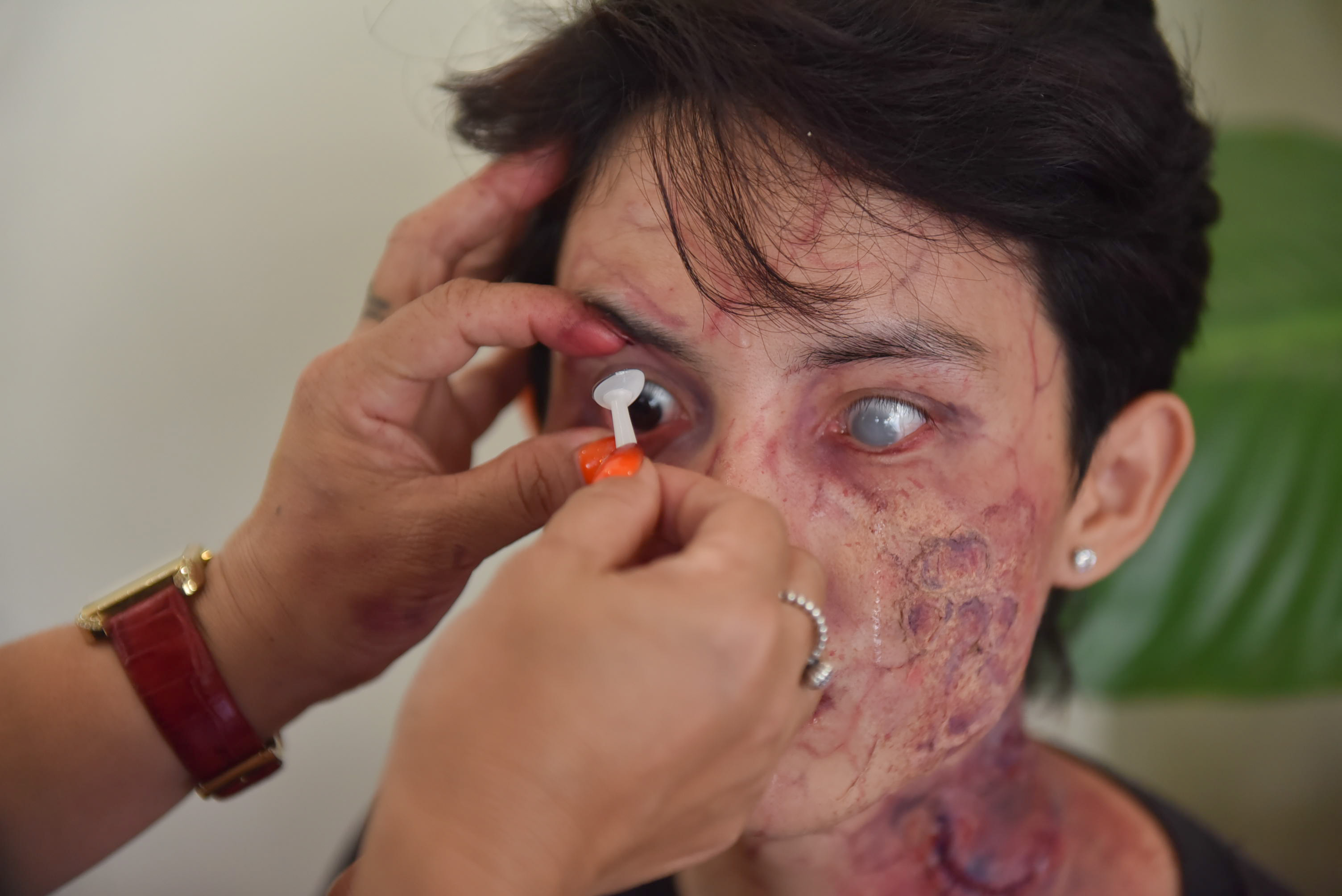 Hang puts white contact lenses to mimic sclera on an actor’s eyes as she transforms him into a zombie. Photo: Ngoc Phuong / Tuoi Tre News