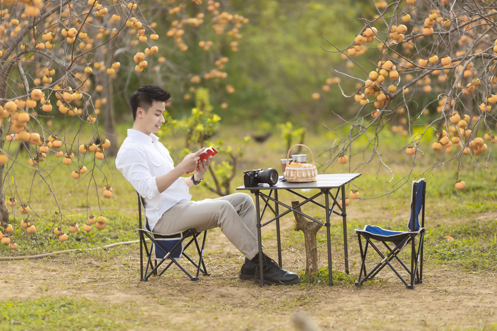 A tourist poses for a photo in a persimmon orchard in Moc Chau Town, Son La District. Photo courtesy of Ngua Hoang