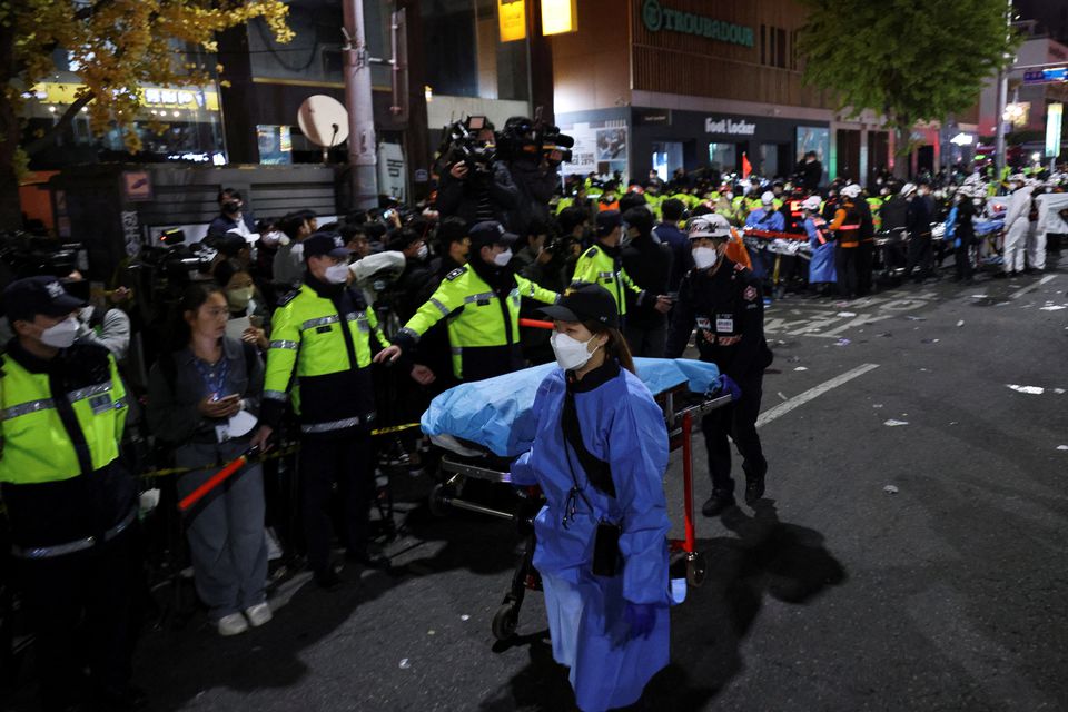 Rescue team members move a body at the scene where dozens of people were injured in a stampede during a Halloween festival in Seoul, South Korea, October 29, 2022. Photo: Reuters