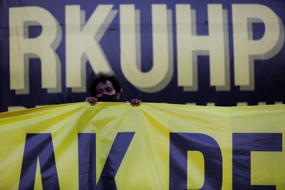 A protester holds a banner during a protest as Indonesia is set to pass a new criminal code that will ban sex outside marriage, cohabitation between unmarried couples, insulting the president, and expressing views counter to the national ideology, outside the Indonesian Parliament buildings in Jakarta, Indonesia, December 5, 2022. Photo: Reuters