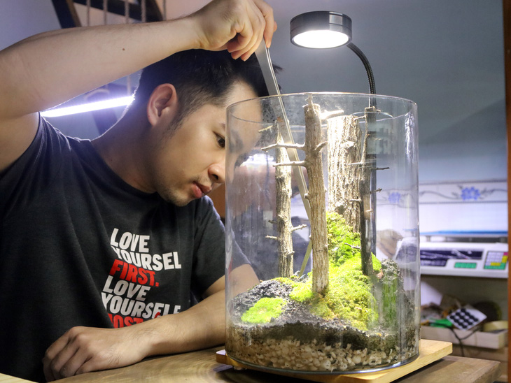 A terrarium maker finalizes his design using specialized tools.