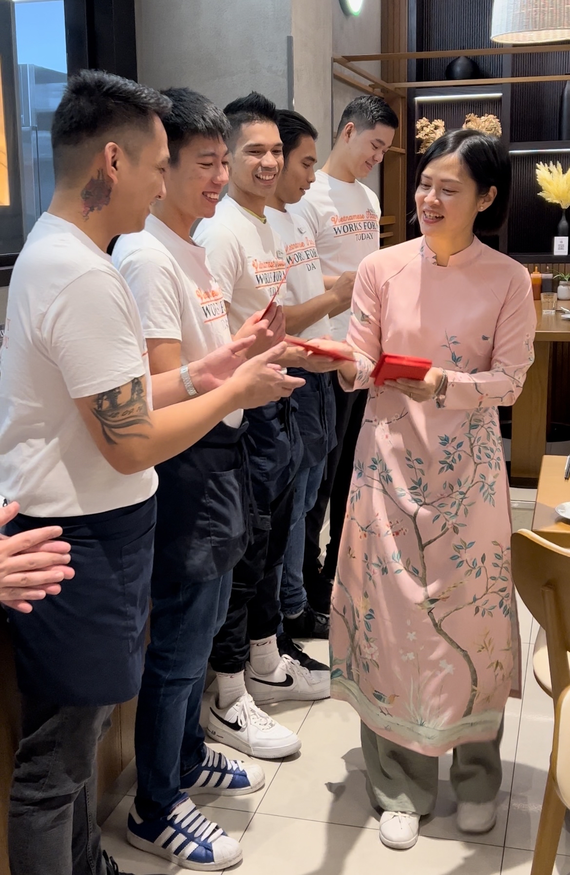 Lily Hoa Nguyen (in ao dai) gives lucky money, a Lunar New Year tradition, to her staff at Vietnamese Foodies in this supplied photo.