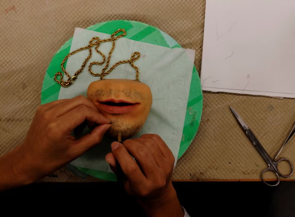 A staff of 'Amazing studio JUR', plants hair on a coin purse shaped like a human's mouth, created by Masataka Shishido, also known as DJ Doooo, during its production at the studio in Tokyo, Japan February 2, 2023. Photo: Reuters