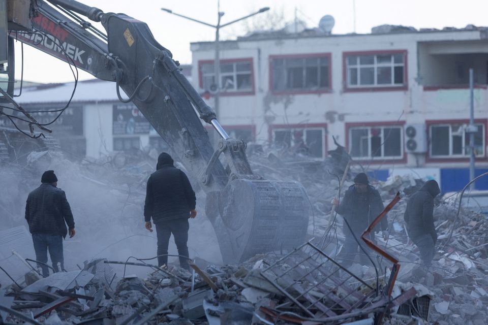 People watch an excavator working in the aftermath of a deadly earthquake in Elbistan, Turkey February 14, 2023. Photo: Reuters