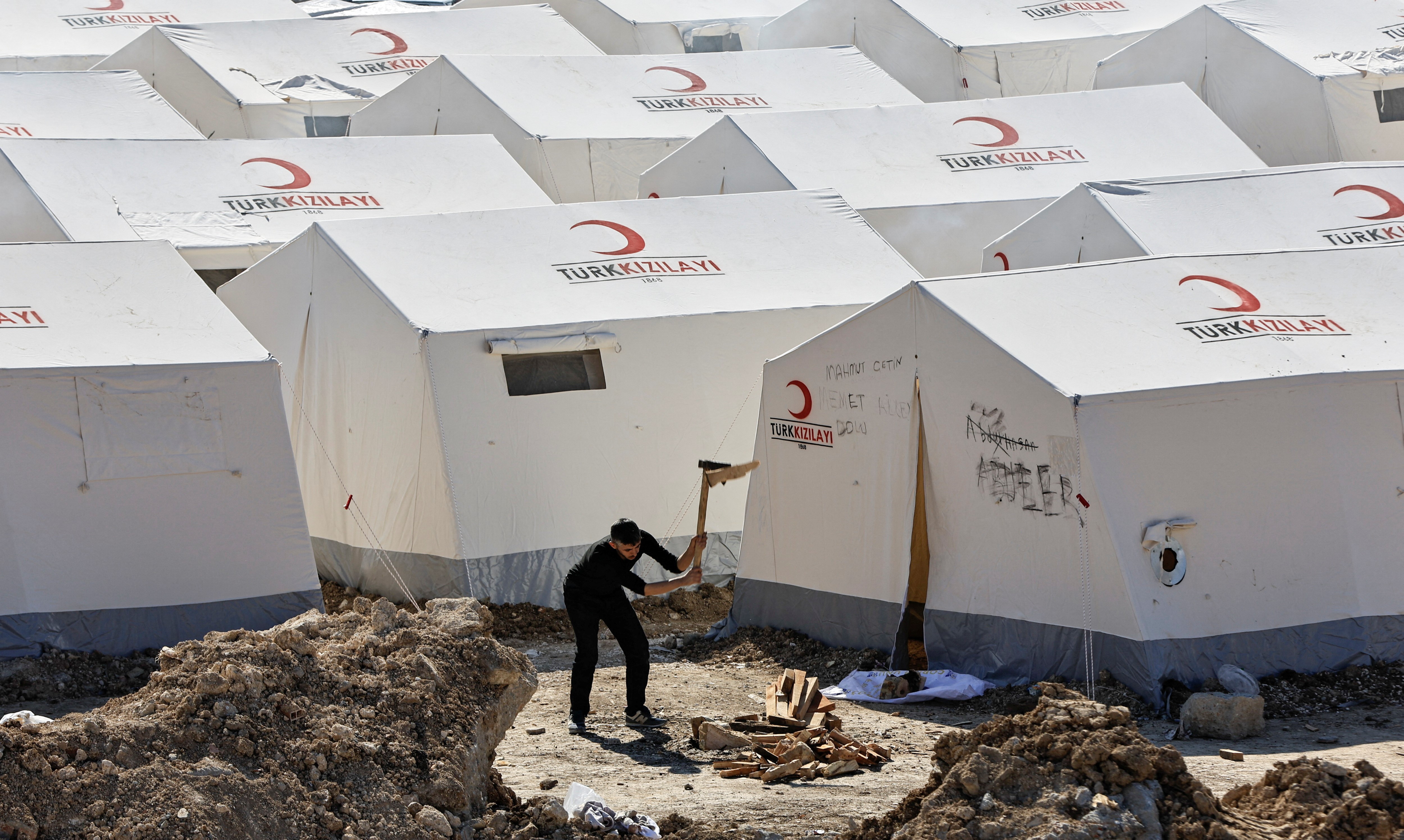 A man chops woods to prepare firewood for heating at a camp for survivors, in the aftermath of a deadly earthquake in Adiyaman, Turkey February 18, 2023. Photo: Reuters