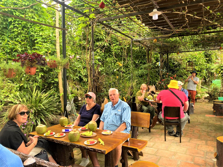 The tourists enjoy traditional cakes and coconut water. Photo: Thuc Nghi / Tuoi Tre