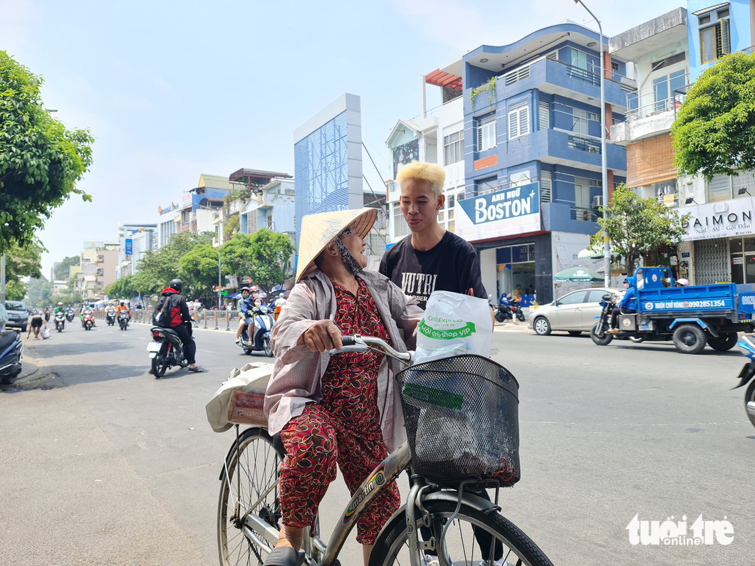 Auntie Nam happily says goodbye to Minh Chanh, a barber taking part in the free haircut program, after she got a new haircut and a gift from the program. Photo: Cong Trieu / Tuoi Tre