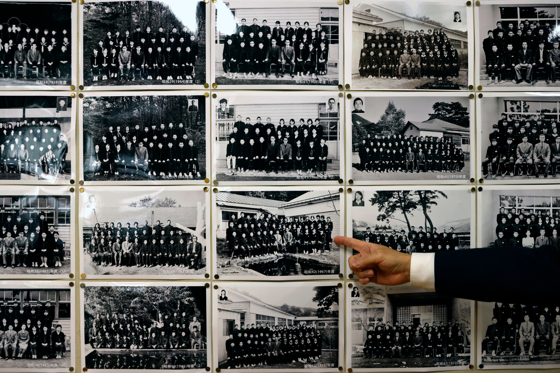 Yumoto Junior High School’s principal Mikio Watanabe, 54, points at old graduation photographs in Ten-ei Village, Japan, March 10, 2023. Photo: Reuters