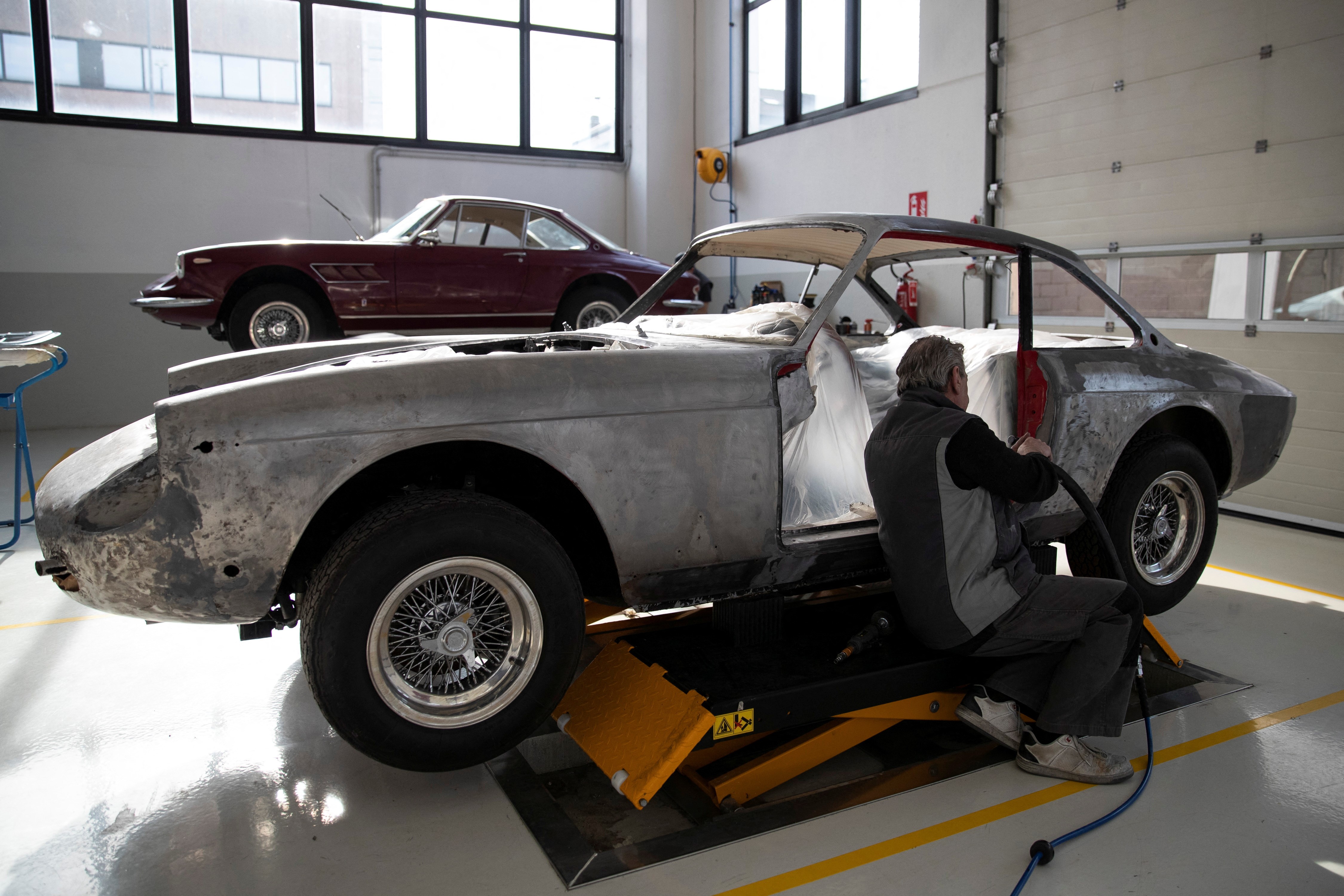 A man works on a Ferrari Classiche car at the Atelier Fiorano, a Rossocorsa authorised bodyshop in Assago, near Milan, Italy, April 6, 2023. Photo: Reuters