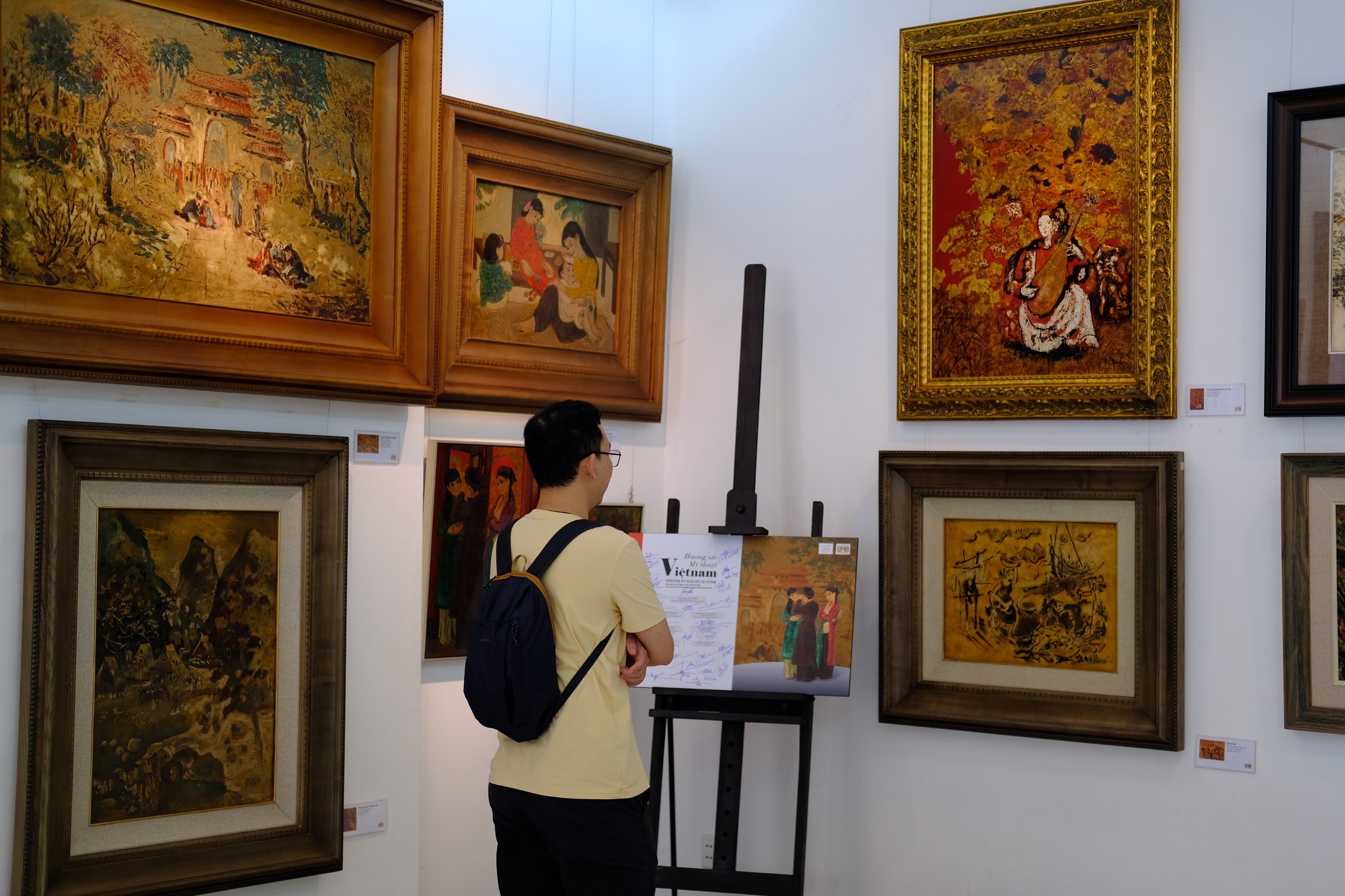 A visitor looks at paintings by Vietnamese artists on display at an exhibition to celebrate the 50th anniversary of the establishment of diplomatic relations between Vietnam and France in Ho Chi Minh City. Photo: Phuong Tran / Tuoi Tre News