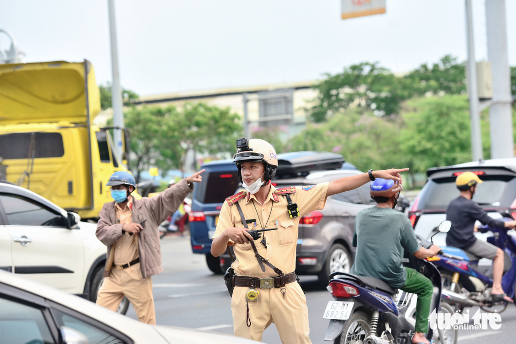 Traffic police officers instruct commuters to loops or alleys to ease overload on National Highway 1. Photo: Duyen Phan / Tuoi Tre