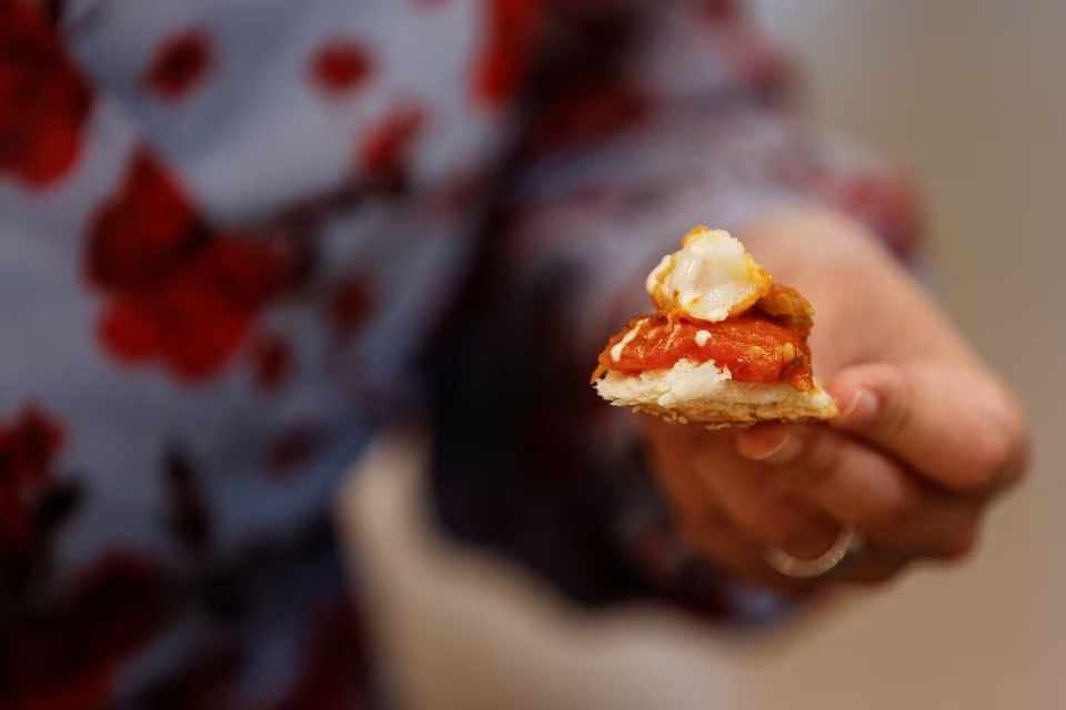 The representative director of Japan Association for Cellular Agriculture holds up a morsel of a dish containing 3D-printed cultivated grouper fish during a tasting at the offices of Steakholder Foods in Rehovot, Israel, April 23, 2023. Photo: Reuters