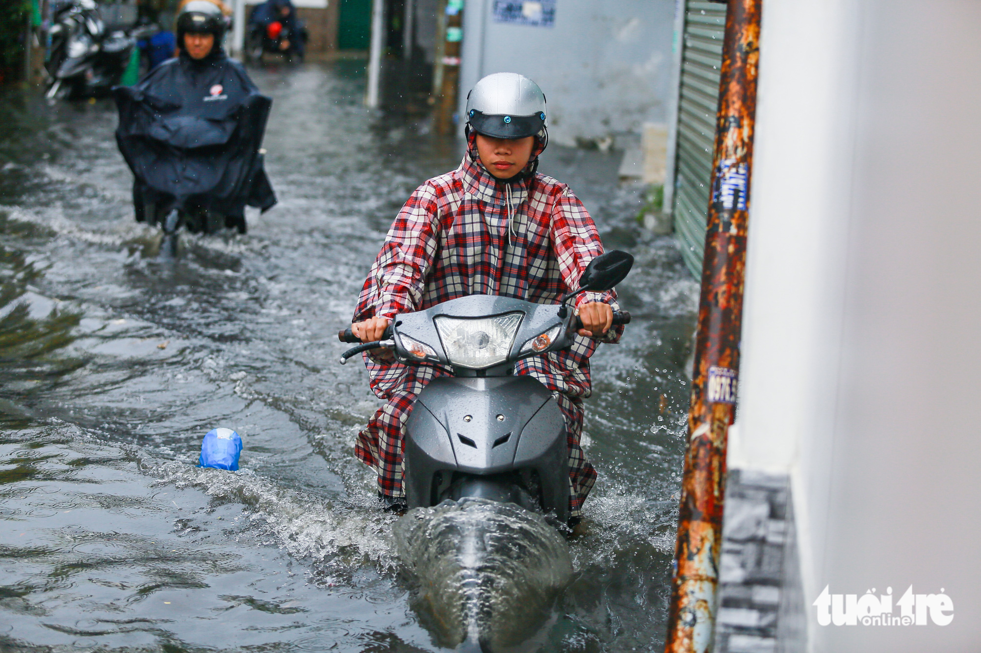 Residents try to commute along a flooded section of To Ngoc Van Street in Thu Duc City. Photo: Chau Tuan / Tuoi Tre