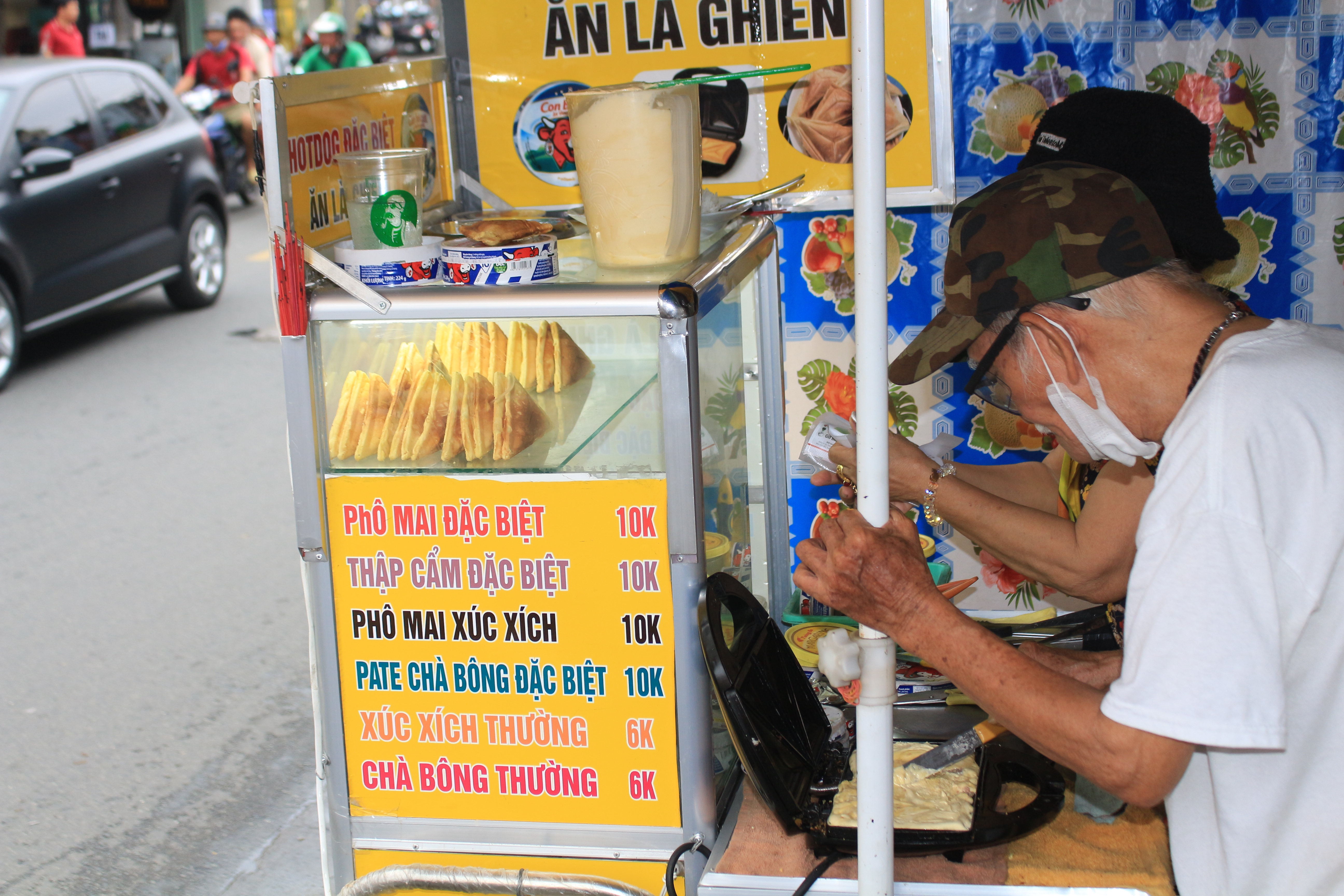 A couple makes Vietnamese-style hot dog using a toasted sandwich maker on the street in Go Vap District, Ho Chi Minh City. Photo: Ray Kuschert / Tuoi Tre News