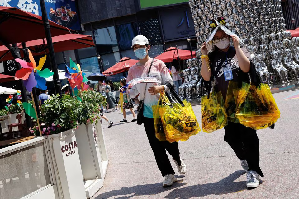 People shield themselves from the sun, as they walk amid a red alert for heatwave in Beijing, China June 23, 2023. Photo: Reuters