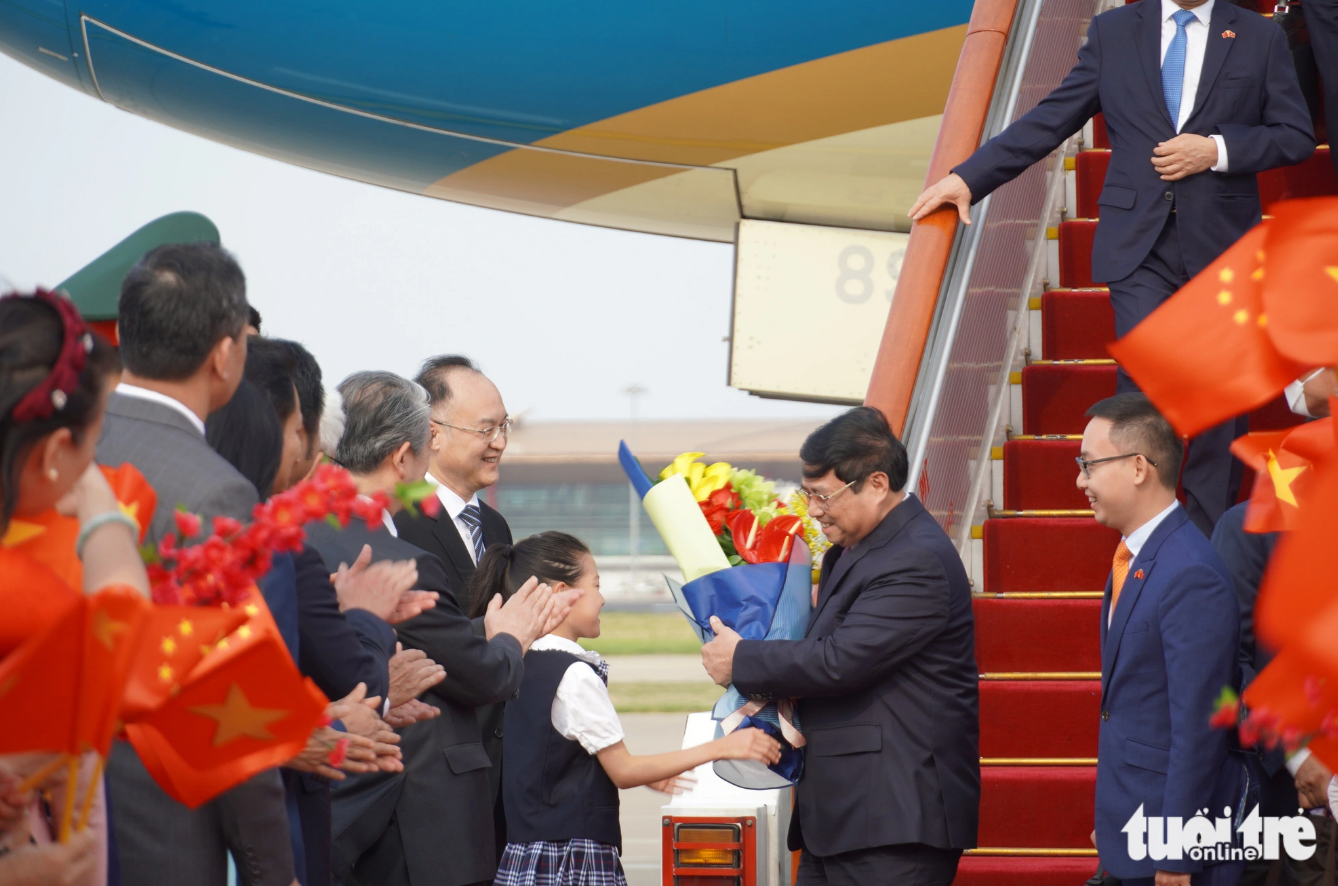 Prime Minister Pham Minh Chinh (second, right) receives a bouquet of flowers from a Chinese child. Photo: Ngoc An / Tuoi Tre