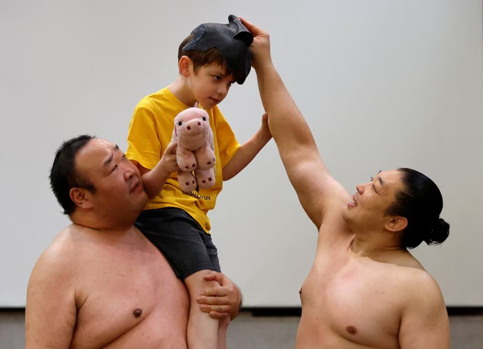 Theo, a 9-year-old child from Australia, tries to spar against former sumo wrestlers Kotoohtori and Towanoyama on the sumo ring before tourists from abroad, at Yokozuna Tonkatsu Dosukoi Tanaka in Tokyo, Japan June 30, 2023. Photo: Reuters