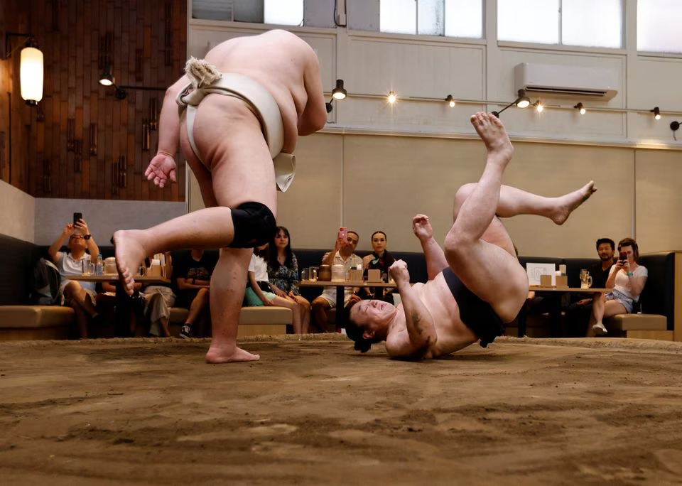 Former sumo wrestlers Kotoohtori, 40, and Towanoyama, 45, engage in sparring before tourists from abroad, on the sumo ring at Yokozuna Tonkatsu Dosukoi Tanaka in Tokyo, Japan June 30, 2023. Photo: Reuters