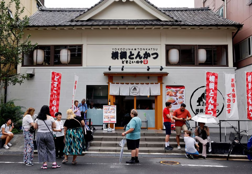 Tourists from abroad wait for Yokozuna Tonkatsu Dosukoi Tanaka, a sumo wrestling themed restaurant to open, in Tokyo, Japan June 30, 2023. Photo: Reuters