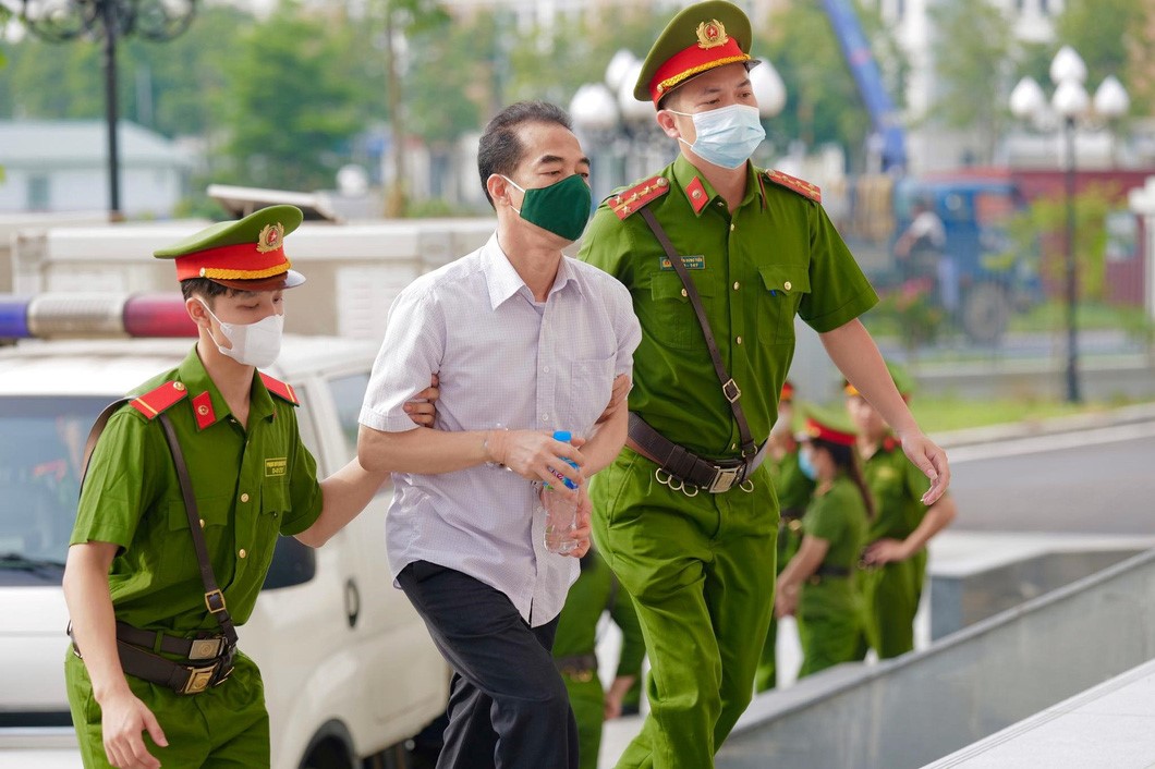 Police officers take former Deputy Minister of Foreign Affairs To Anh Dung (C) to the court in Hanoi. Photo: Danh Trong / Tuoi Tre