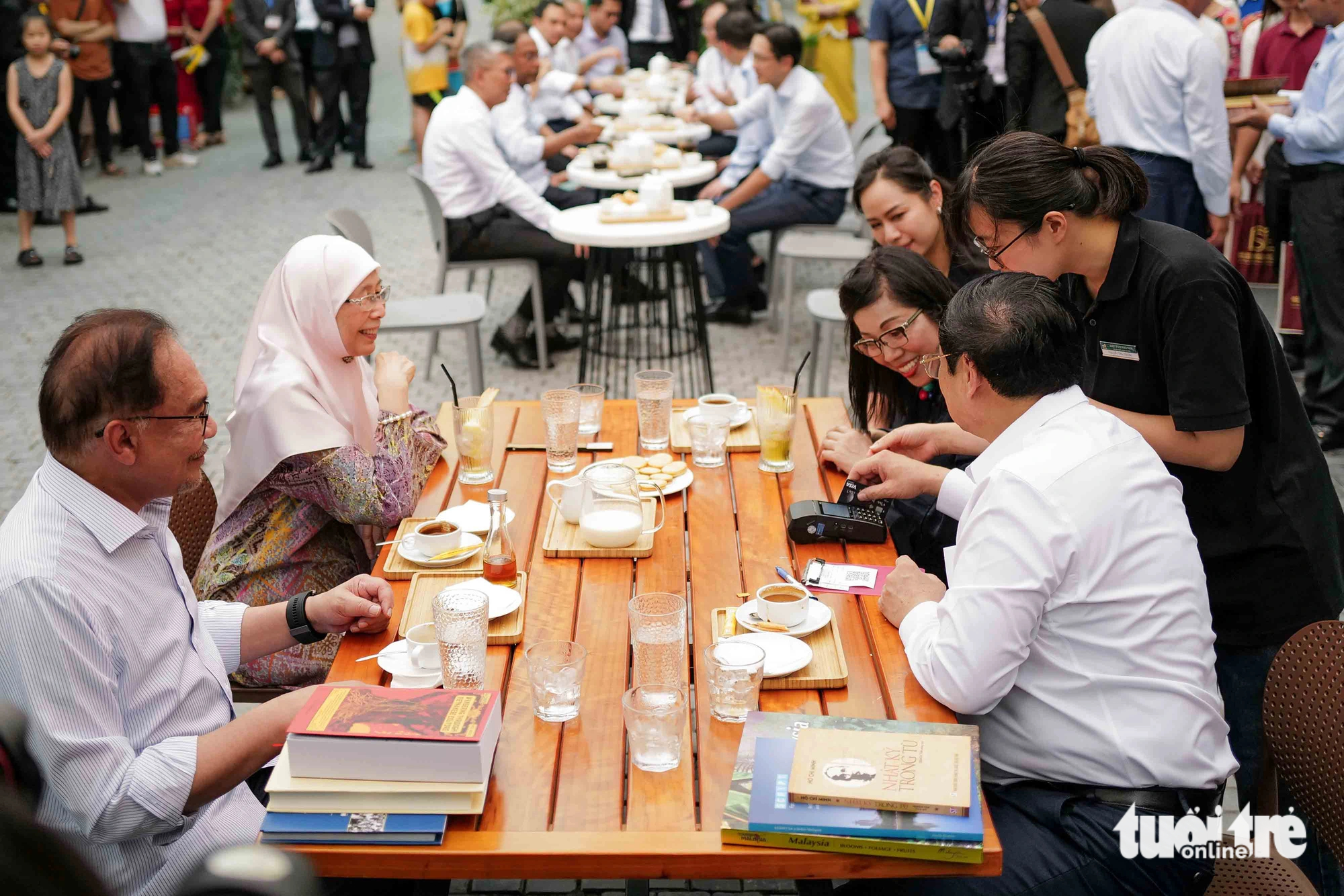 PM Chinh scans a bank card to pay for drinks at a terrace cafe at the 19-12 book street in Hanoi, July 21, 2023. Photo: Nguyen Khanh / Tuoi Tre