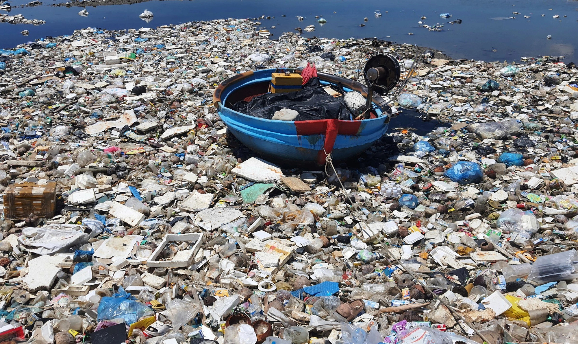 A coracle gets stuck in a large amount of trash in the Sa Huynh salt lagoon.  Photo: TR.M / Tuoi Tre